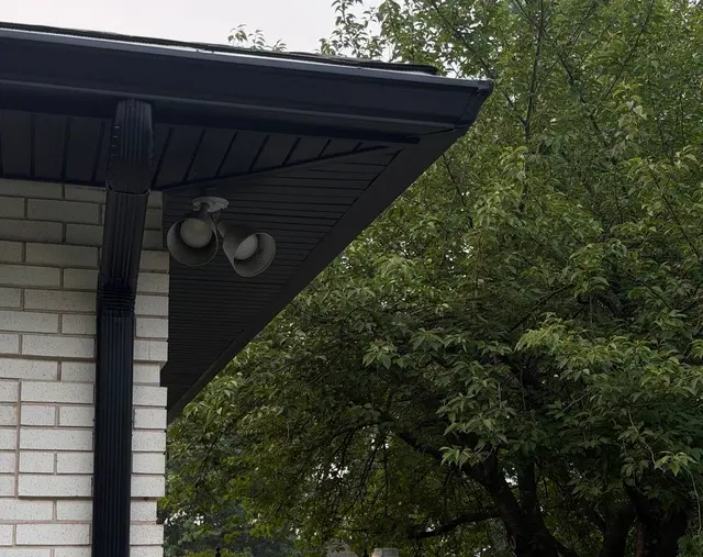 Black seamless gutter and downspout at the corner of a white brick home in Pennsylvania