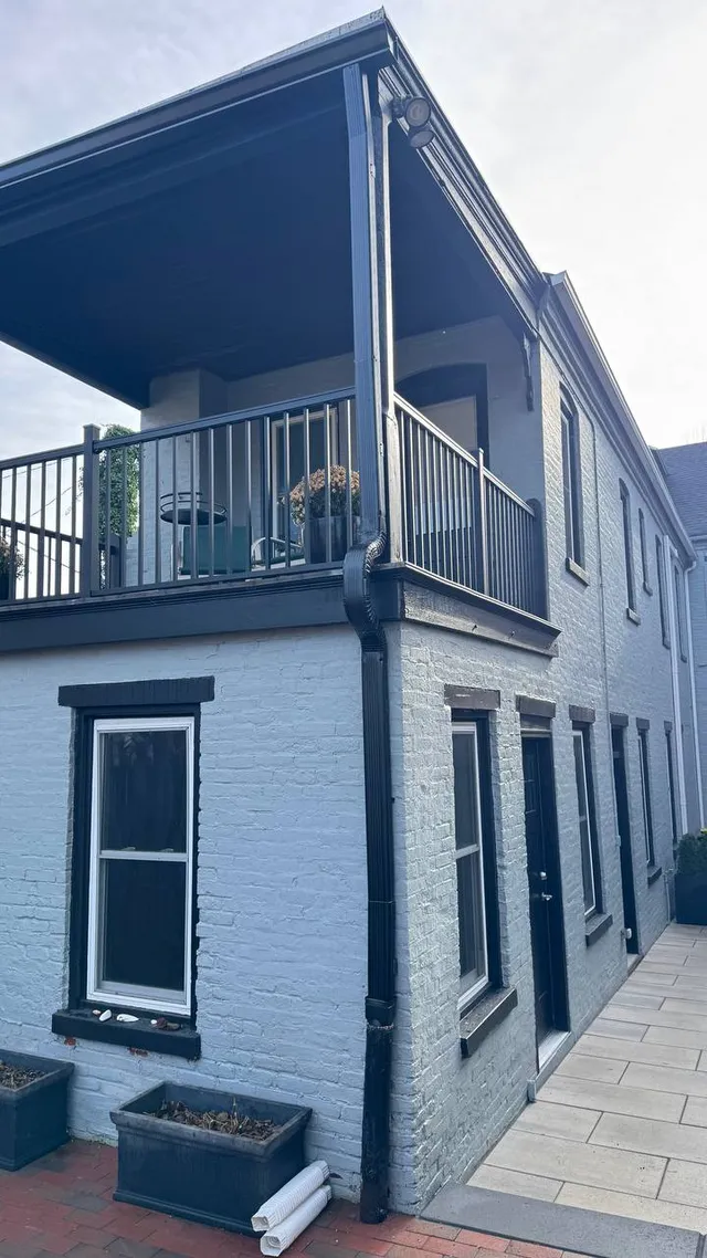 Black seamless gutters and downspout on a painted brick home with balcony in Pennsylvania