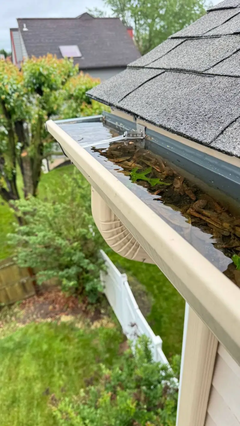 Clogged gutter overflowing with standing water and leaf debris on a Bucks County home