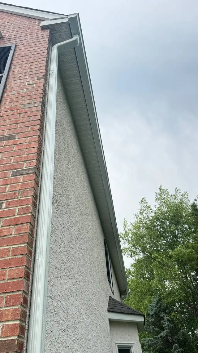 Seamless white gutter and downspout detail on a stucco and brick Pennsylvania home