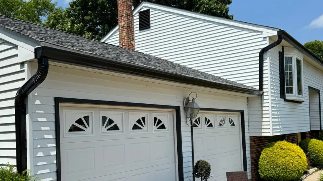 Black seamless gutters and downspout on a white garage in Bucks County