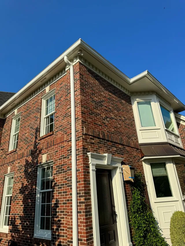 Seamless white gutters installed along the roofline of a brick home in Pennsylvania